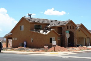 A construction worker works on a roof while another looks at an air conditioner unit at a new home in Dixie Springs, Washington County, Utah, July 25, 2013 | Photo by Reuben Wadsworth, St. George News