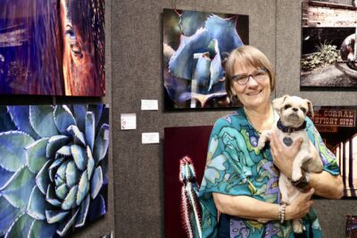 Kay Lynn Reilly stands in front of her photography with her dog, Ivins, Utah, May 15, 2022 | Photo by Jessi Bang, St. George News