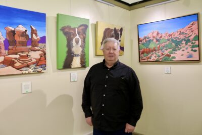 Artist Ken Church stands by his paintings inside Arrowhead Gallery, St. George, Utah | Photo by Jessi Bang, St. George News