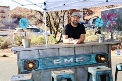 Aaron Mathews stands next to his custom furniture design at the Tuacahn Saturday Market in Ivins, Utah, Feb. 4, 2023 | Photo by Jessi Bang, St. George News