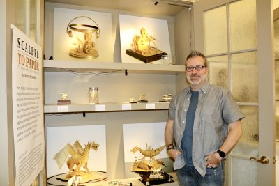Artist and author Charlie Pulsipher poses next to his art exhibit at Art Provides in St. George, Utah, June 28, 2023 | Photo by Jessi Bang, St. George News