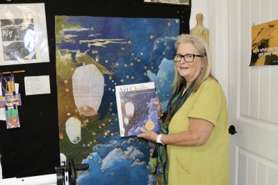 Textile artist Margaret Abramshe takes a photo next to her artwork that is also featured in a magazine, St. George, Utah, Sept. 21, 2023 | Photo by Jessi Bang, St. George News