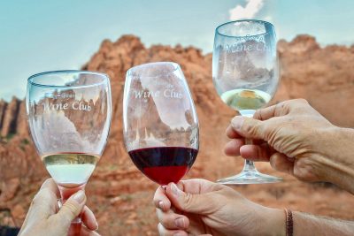 Members of the St. George Wine Club clink their wine glasses together against a red mountain backdrop, location and date unspecified | Photo courtesy of Marianne Hamilton, St. George News