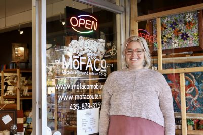 MoFACo founder and owner Kay Puzey takes a photo in front of the shop that has helped over 90 local artistans, makers and farmers support their families for the last three years, St. George, Utah, Nov. 21, 2023 | Photo by Jessi Bang, St. George News