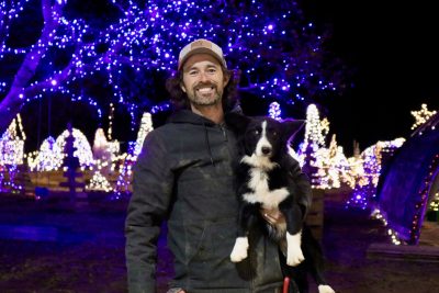 Payton Fisher holds his farm dog in front of thousands of Christmas lights that are hung for the Deck the Halls Festival, Hurricane, Utah, Nov. 27, 2023 | Photo by Jessi Bang, St. George News