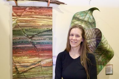 Textile Artist Teri McHale's stands next to her layered wall art at the Arrowhead Gallery in St. George, Utah, Feb. 22, 2024 | Photo by Jessi Bang, St. George News