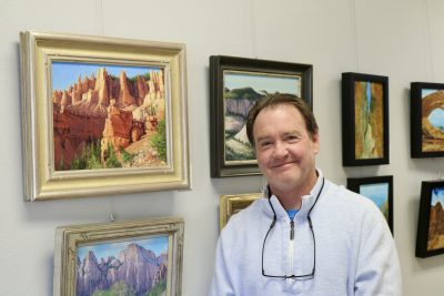 Artist Travis Humphreys stands next to his framed art inside Red Cliffs Gallery in St. George, Utah, Feb. 27, 2024 | Photo by Jessi Bang, St. George News