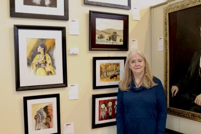 Artist Cheryl Sachse stands next to her work showcased inside the Arrowhead Gallery in St. George, Utah, Feb. 27, 2024 | Photo by Jessi Bang, St. George News
