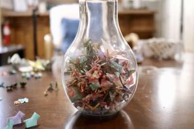 A jar full of origami cranes sits on a table surrounded by other folded art, Hurricane, Utah, April 15, 2024 | Photo by Jessi Bang, St. George News