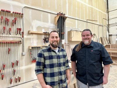 L-R: Mad Metal Fabrication owner Jordan Madsen and Axios Studios Jeremy Peterson smile for the camera inside their shop in St. George, Utah, May 2, 2024 | Photo by Jessi Bang, St. George News