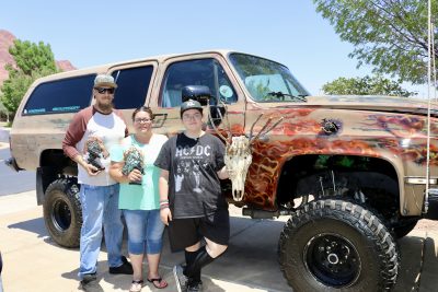 Ray Patten, wife Brittany Patten and daughter Nevaeh Thompson stand next to their rat rod-style suburban holding art pieces, Ivins, Utah, June 16, 2024 | Photo by Jessi Bang, St. George News